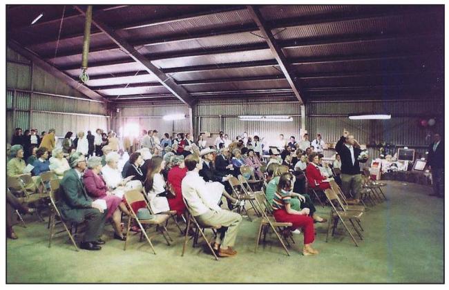A large crowd gathers for the live auction at the first Big Event on March 28, 1982. This is the Tin Building Theatre before it was finished out with dropped ceiling, stage, or central heating and air. Photo Courtesy of the BAC Scrapbook